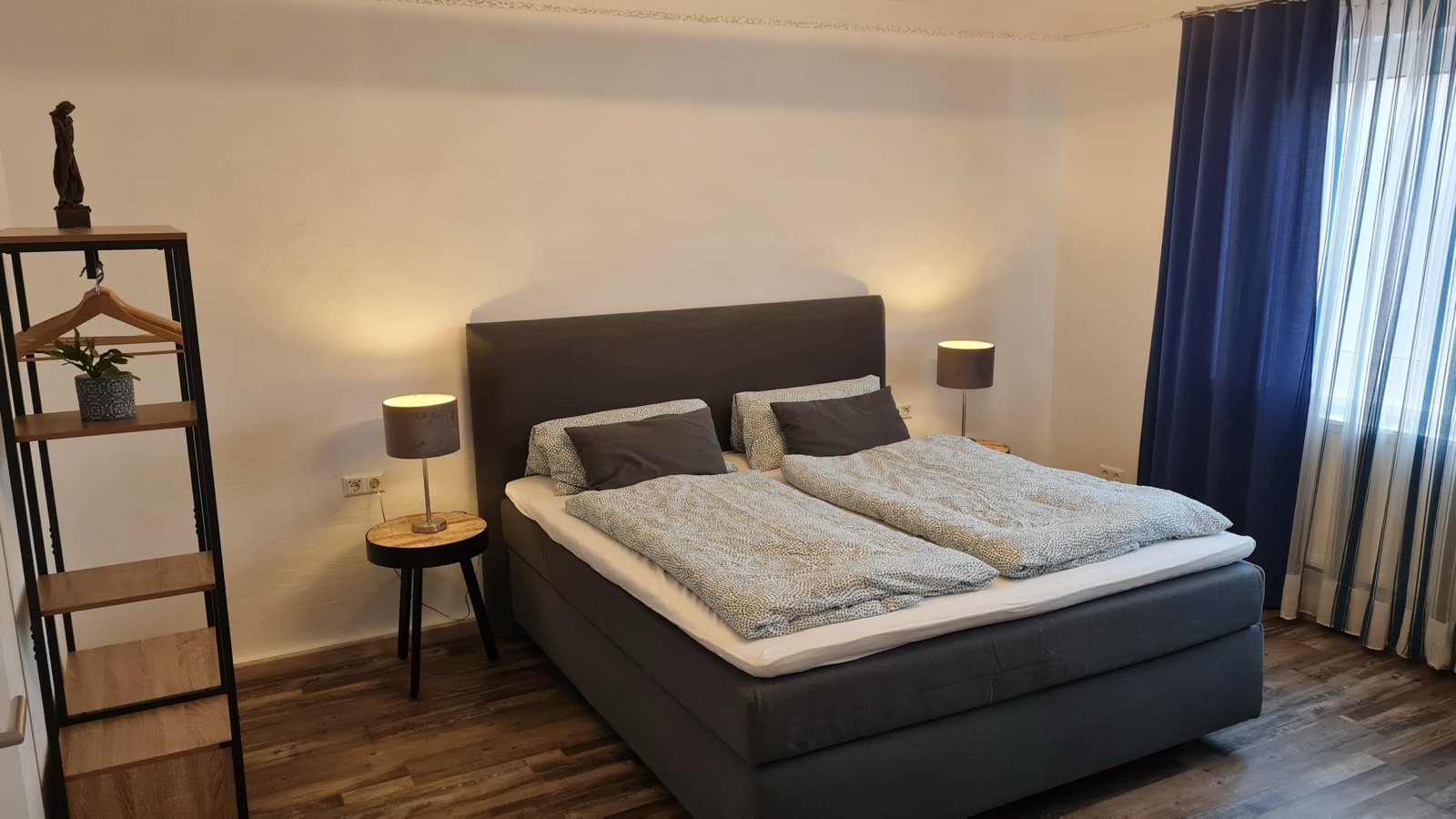Boxspringbett mit dunkelblauen Vorhängen in Zimmer 9 des dillhotel